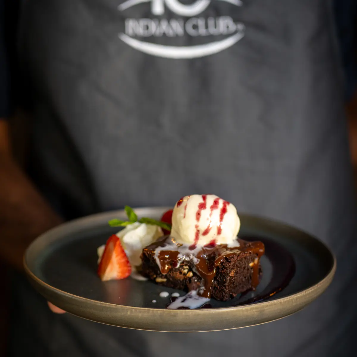 Server presenting desert dish with ice cream.